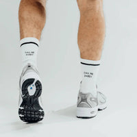 Person wearing white socks with text and sneakers on a light background